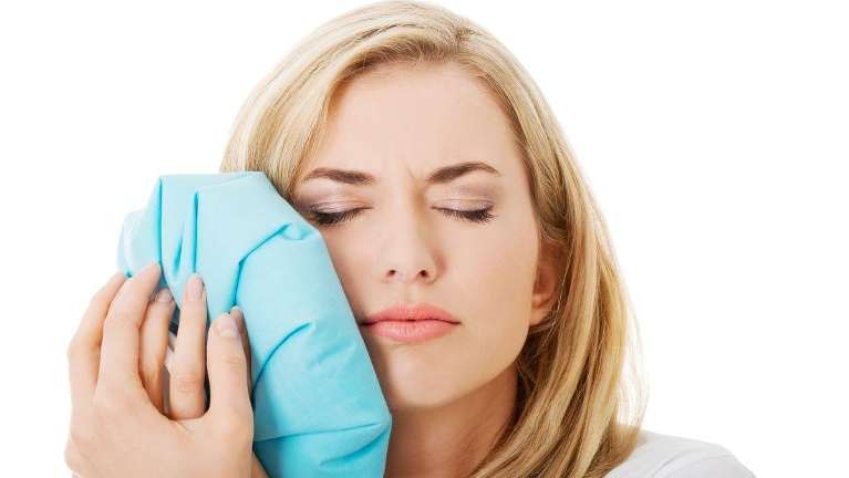Woman holding an ice pack against her jaw, Fontana CA